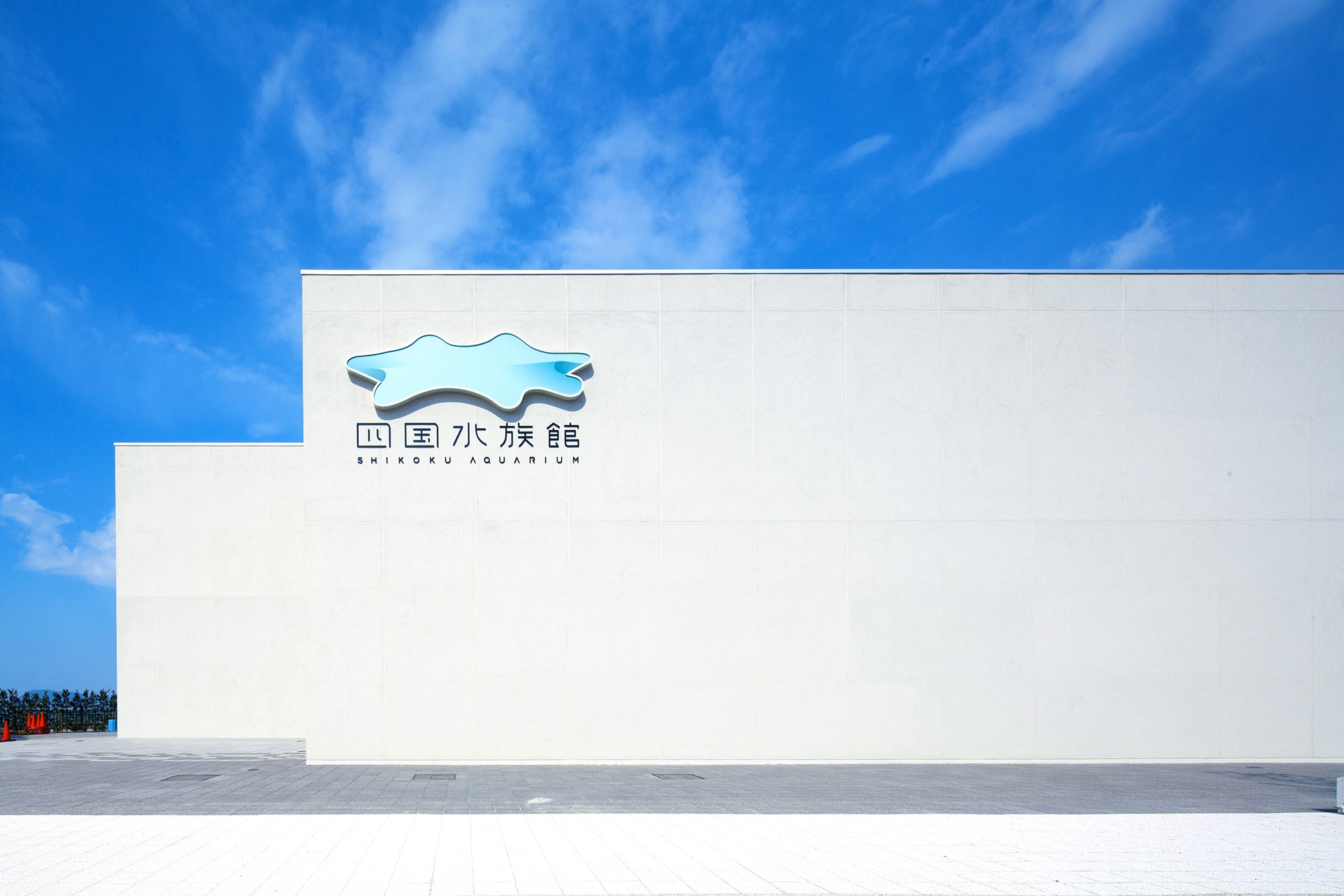 四国水族館：歴史ある宇多津町の塩田をイメージした質感のある外壁。「水のしずくが四国を形作る情景」をコンセプトに造形されたサインには照明が組み込まれており、夕景は昼間と異なる印象を与える。